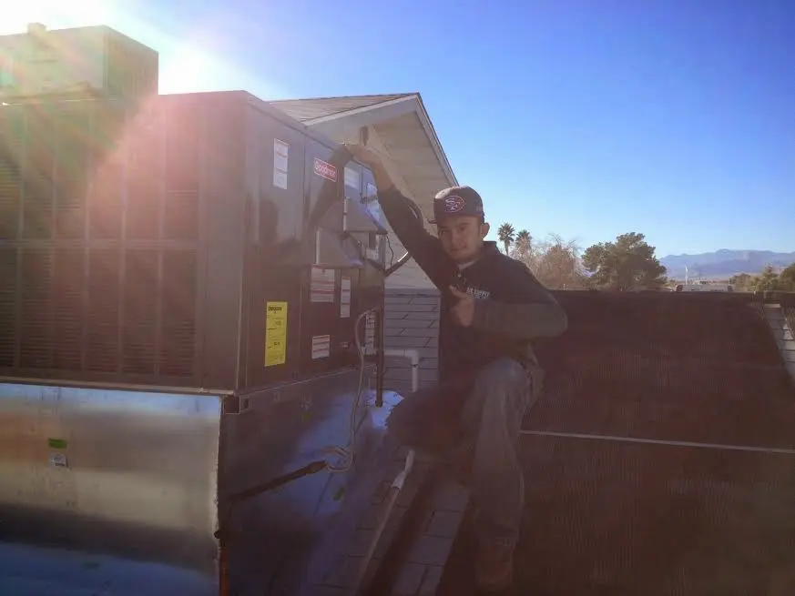 HVAC technician performing Air Duct Cleaning on a rooftop unit in Gloucester